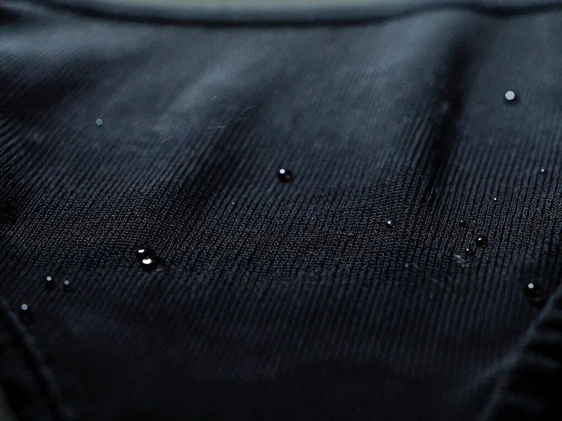 Gros plan sur un tissu extensible de maillot aux fines mailles et gouttelettes